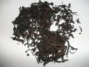 Lá hồng trà khô màu nâu đen rải trên nền trắng